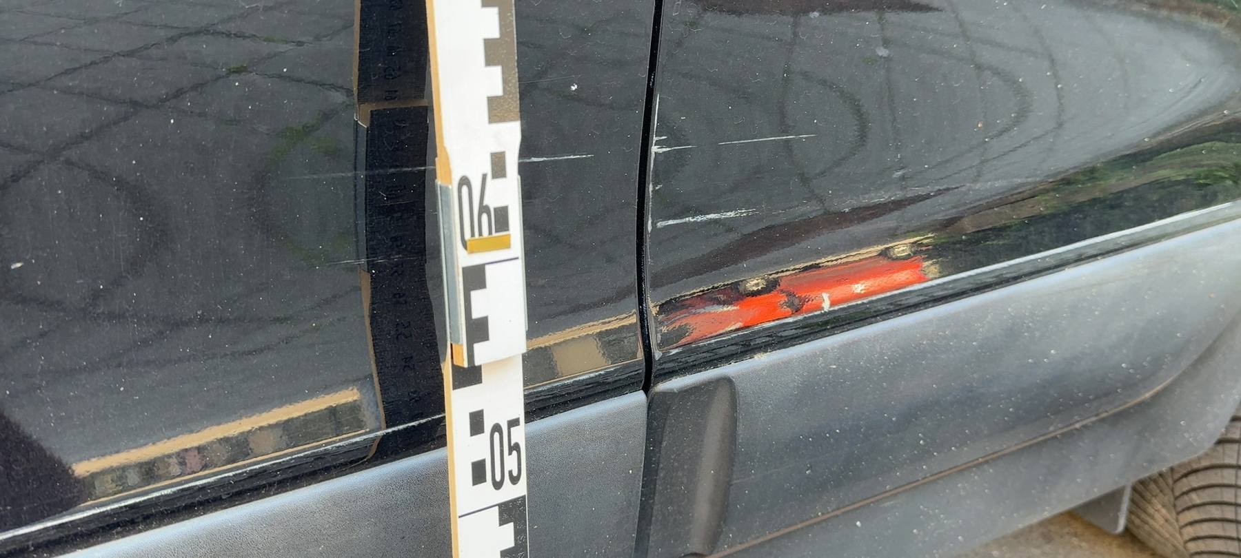 Oranger Fremdlack auf der dunklen Flanke eines Hyundai ix35, Beschädigung über beide Türen