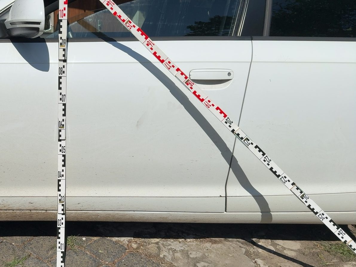 Aufnahme eines Schadenbereichs mit angelegter Messlatte an einem Unfallfahrzeug